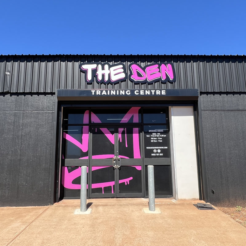 Black Building with Black, White, and Pink The Den Training Centre signage and window/door signage installed by C Signs in Karratha. 